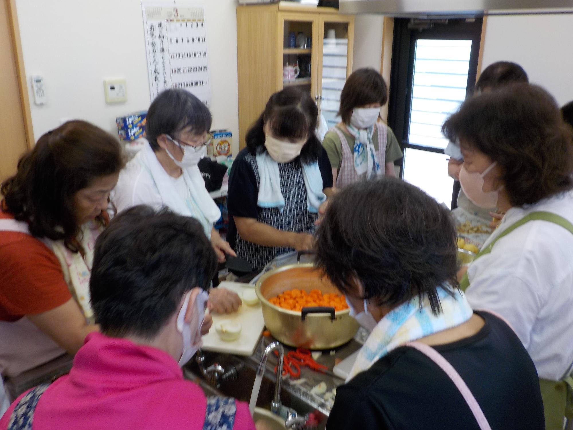 部屋の中で女性たちがカレー作りをしている写真
