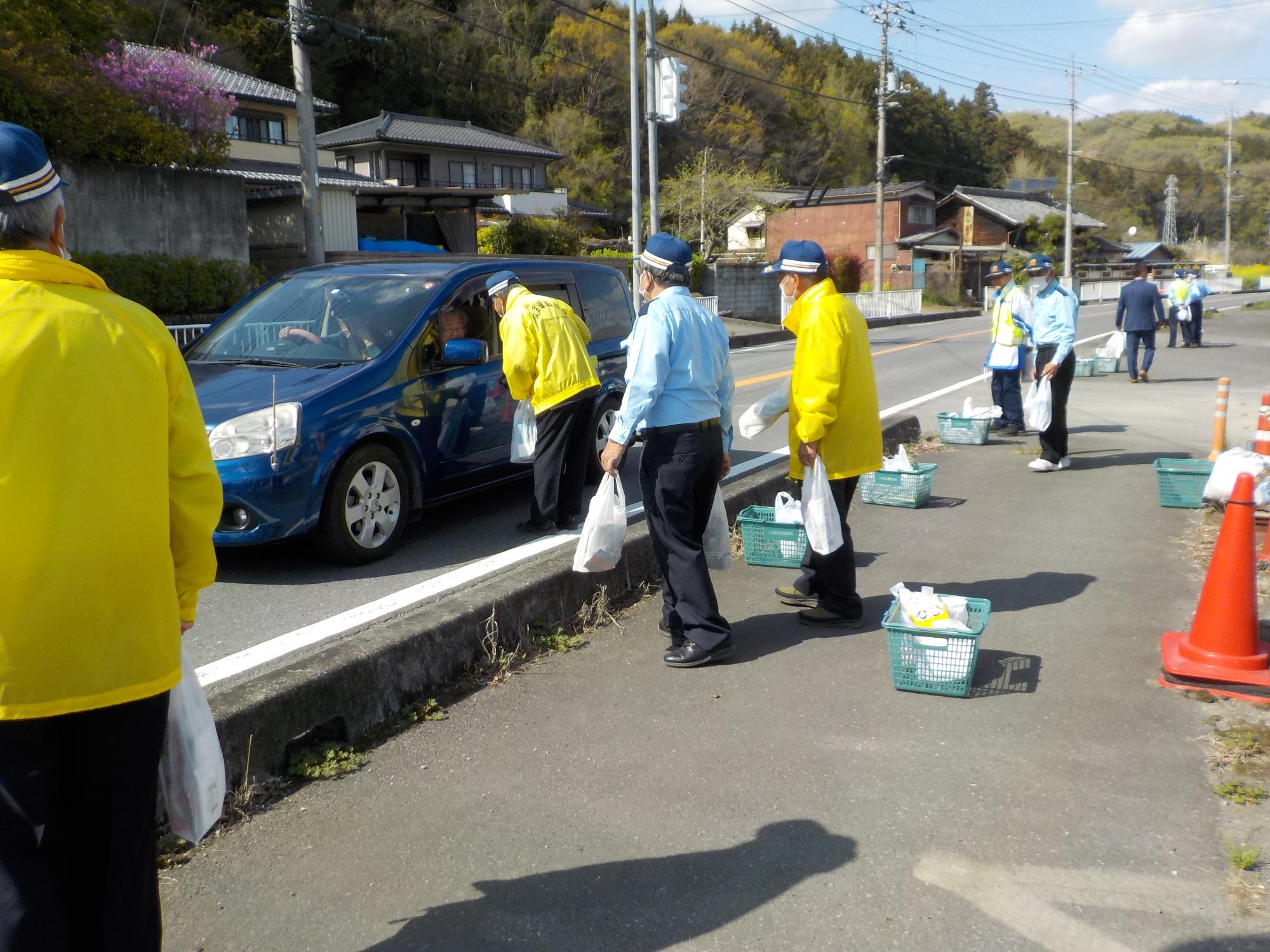 周りの男性たちが地図を手に見ている中、おばあちゃんと孫のような男の子が机の上の地図を見ながら指さして話している様子を撮影した写真