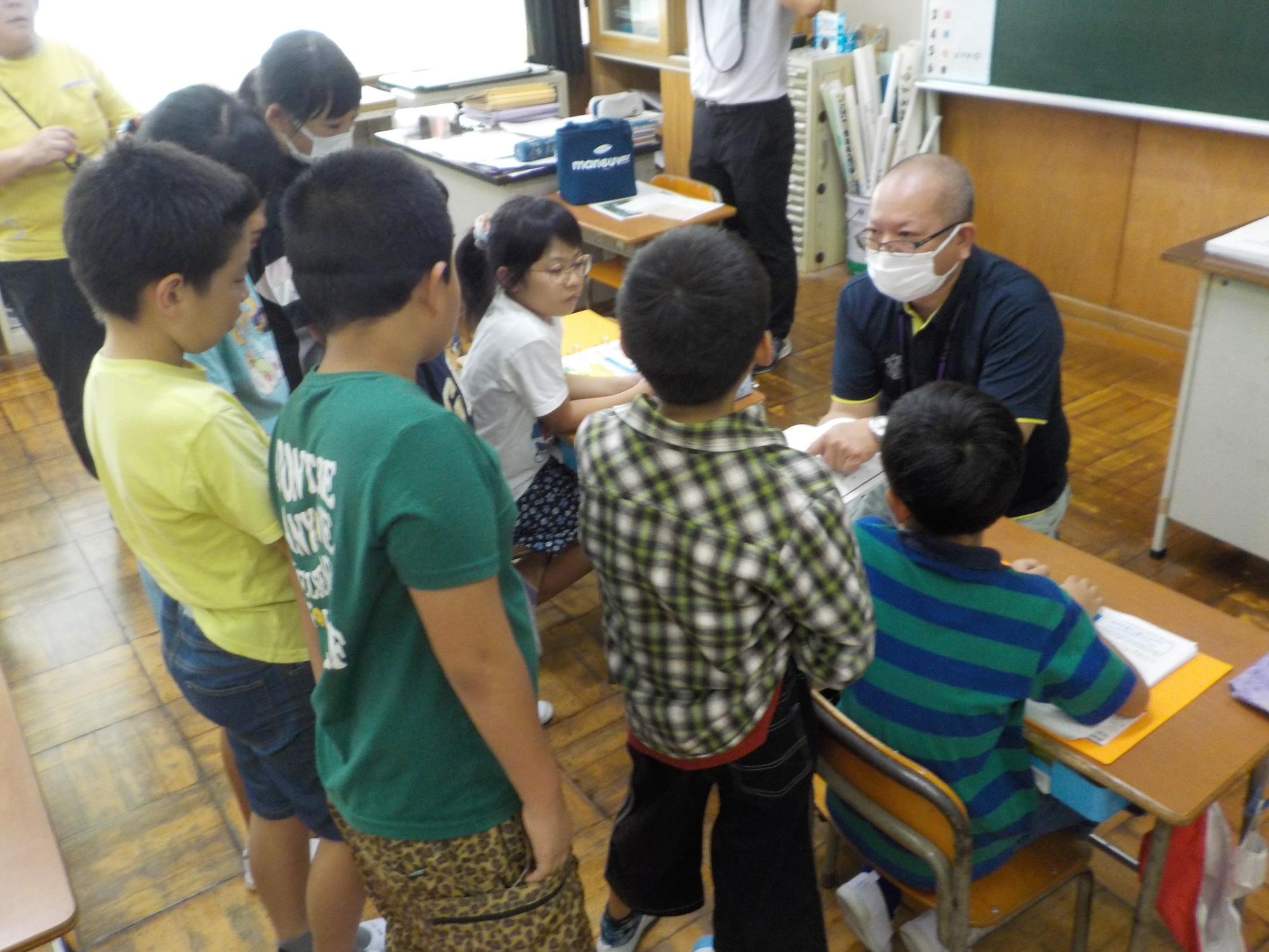 講師の男性の近くにたくさんの子供たちが集まっている写真