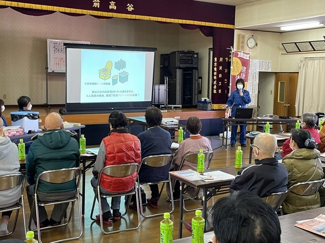 部屋の中で参加者たちが長机の前の椅子に座って防災講座を受けている写真