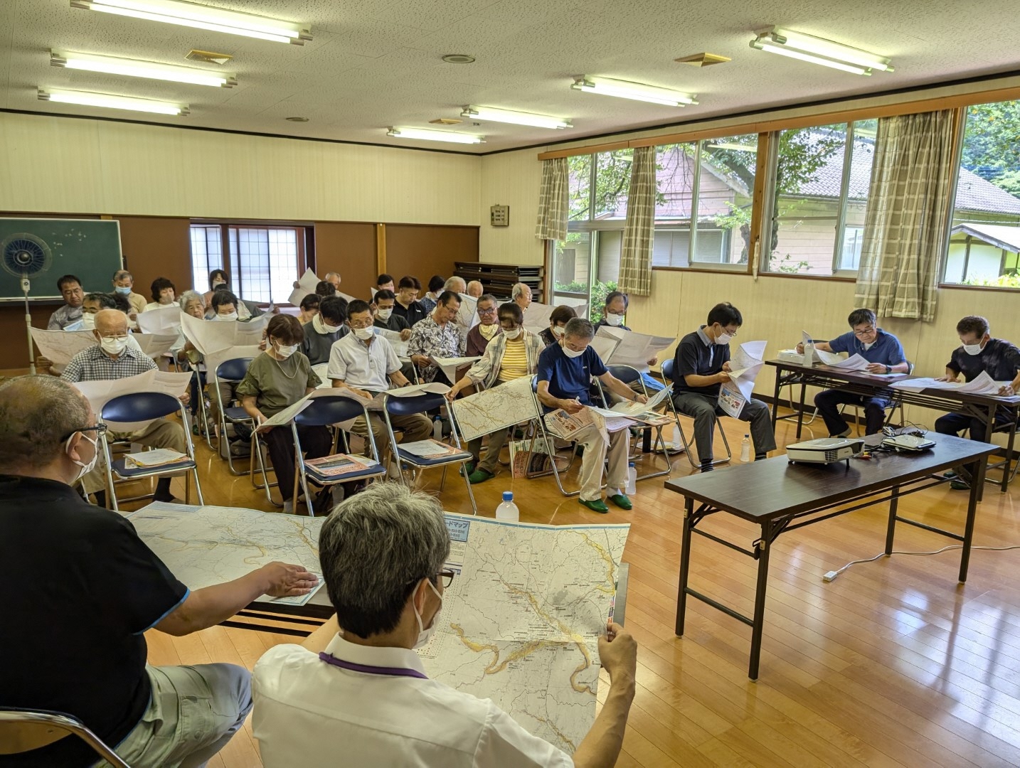 受講者の方々がハザードマップを手に地域特性の説明を聞いている様子を前方から撮影した写真