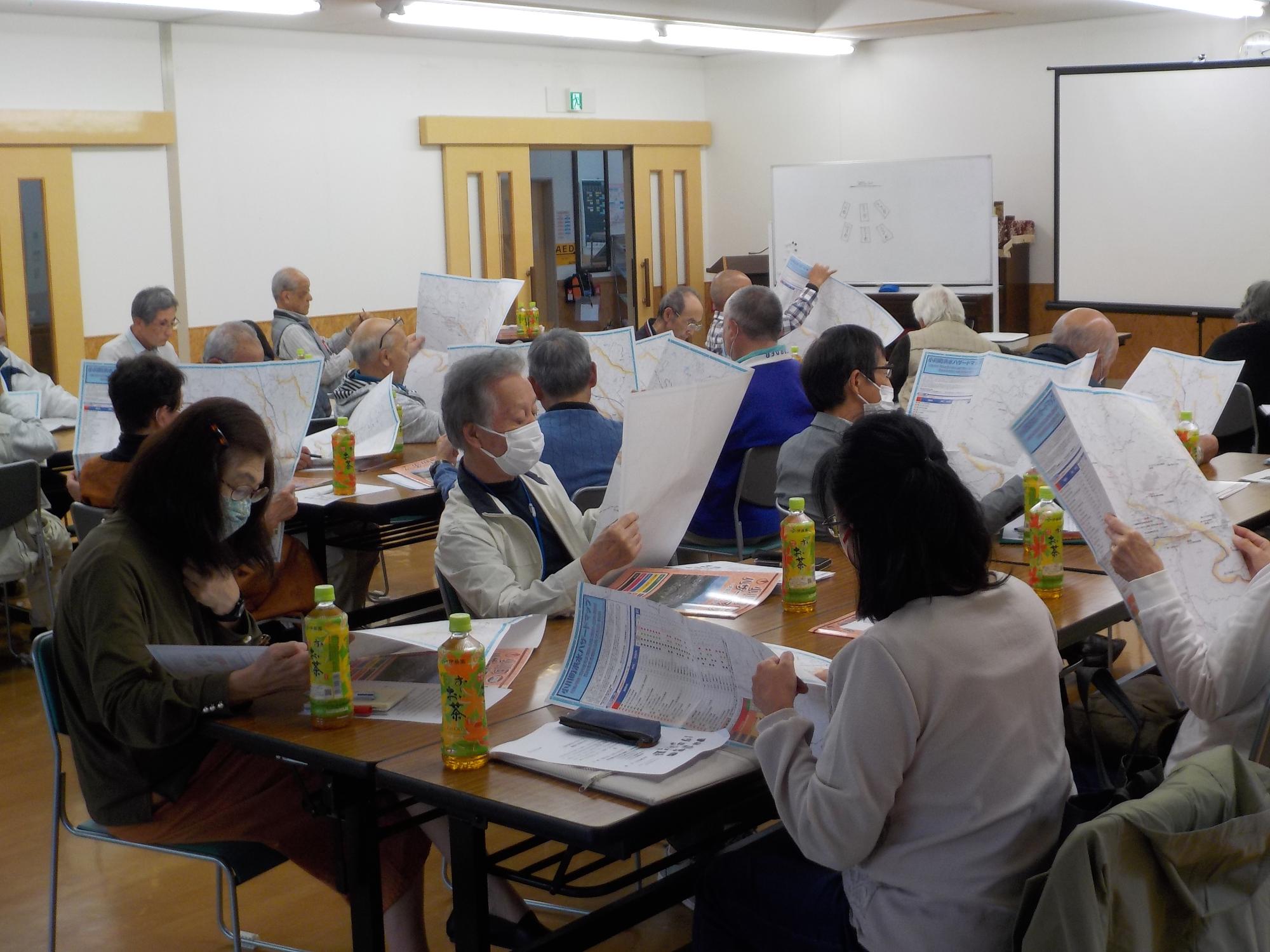 参加者たちがそれぞれ手に持ったハザードマップを見ている写真