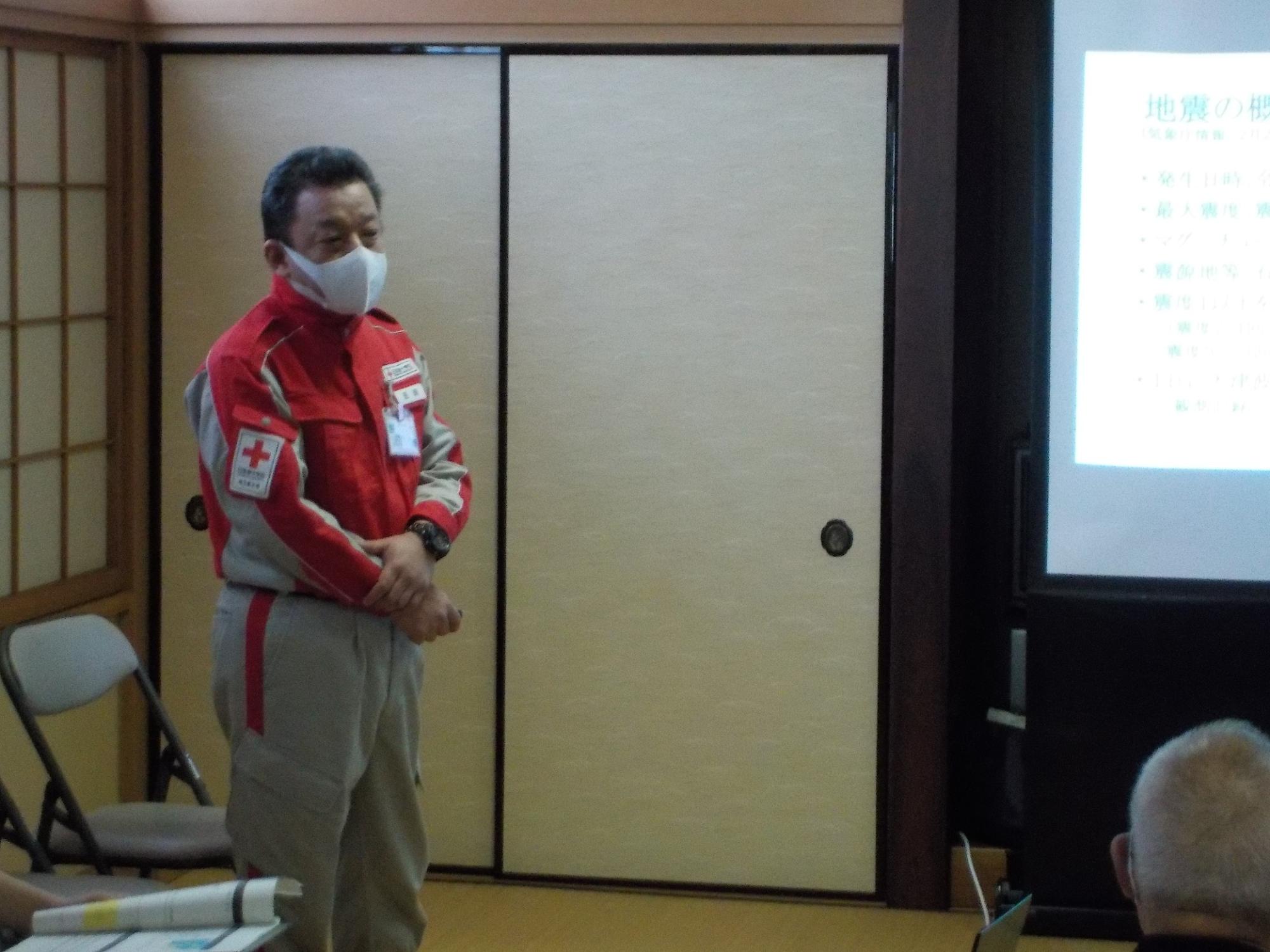 スクリーンの横に立って話す吉田医師の写真