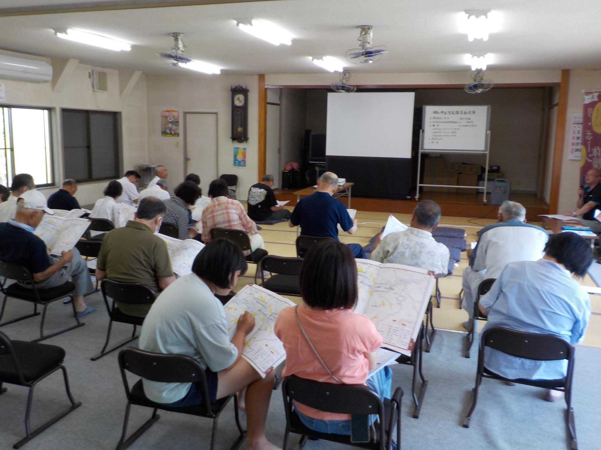 椅子に座った参加者の方々が手にするハザードマップを熱心に見ている様子を後方から撮影した写真