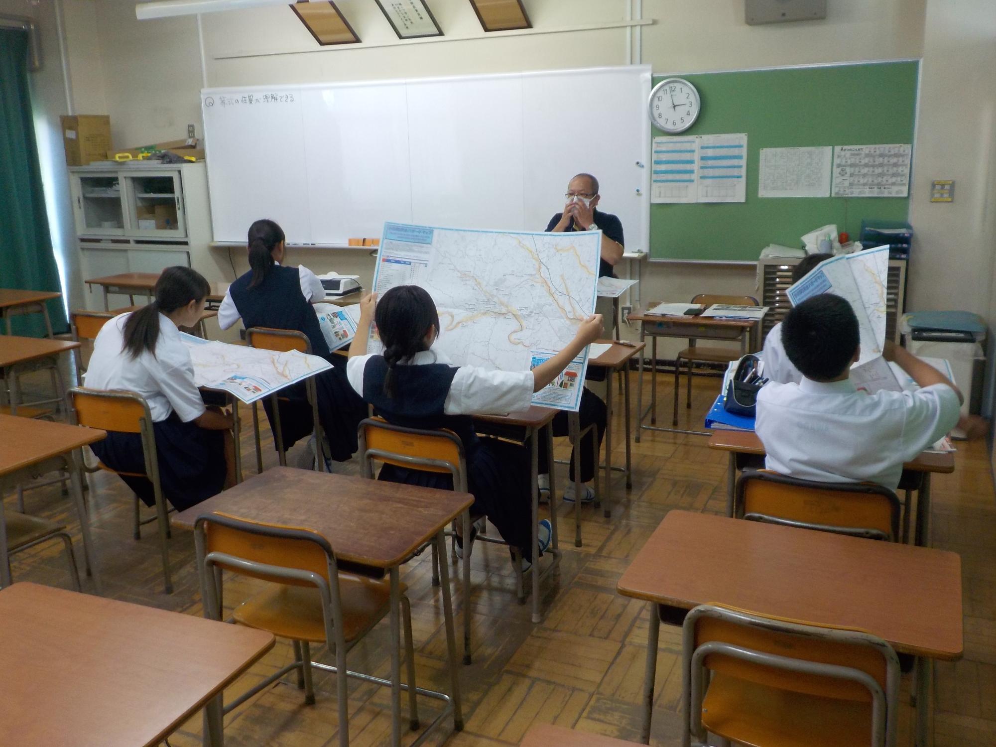 席に座っている生徒達が各自ハザードマップを広げ、見ている写真
