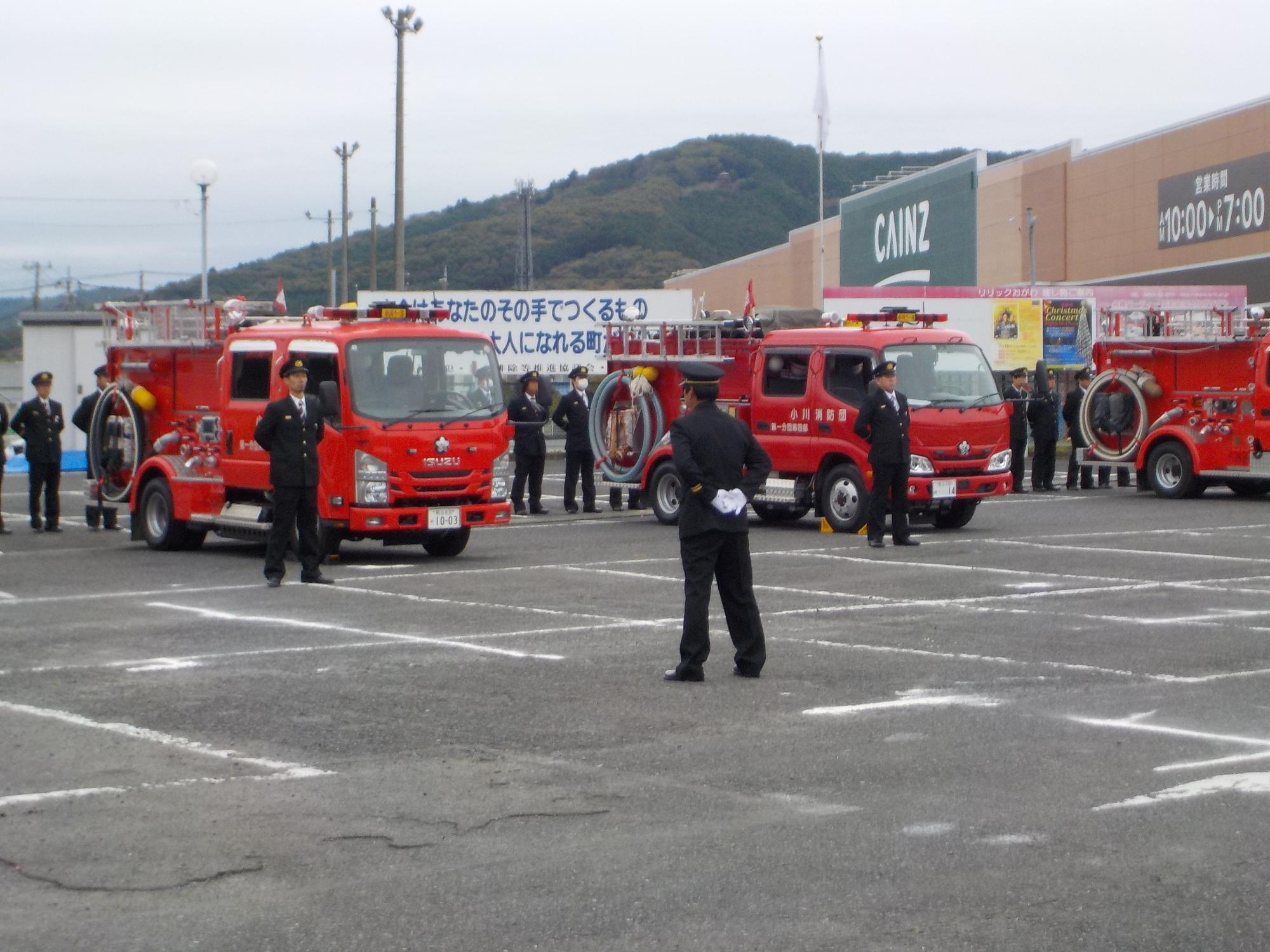 消防団員たちが消防車が停められた駐車場で機械器具の点検を行っている写真
