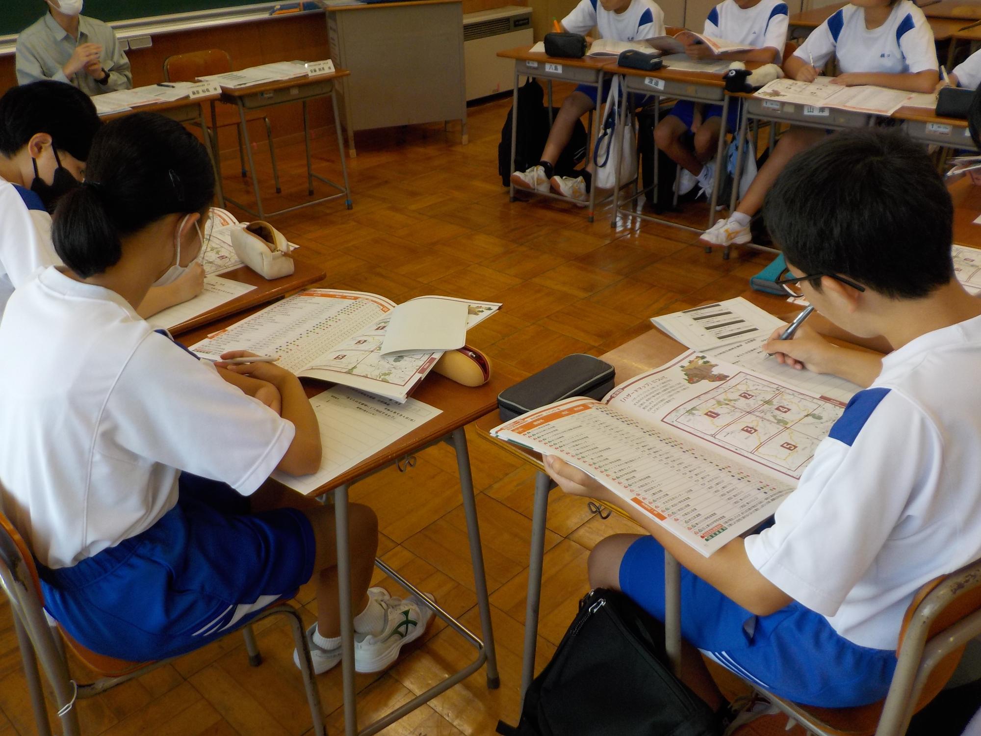 席に座っている生徒達が、机の上に広げられた資料を見たり、メモを取っている様子の写真