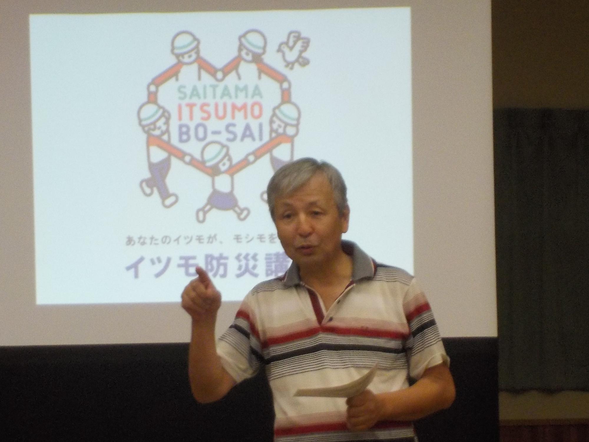 スクリーンの前に立ち挨拶をしている細井副区長の写真