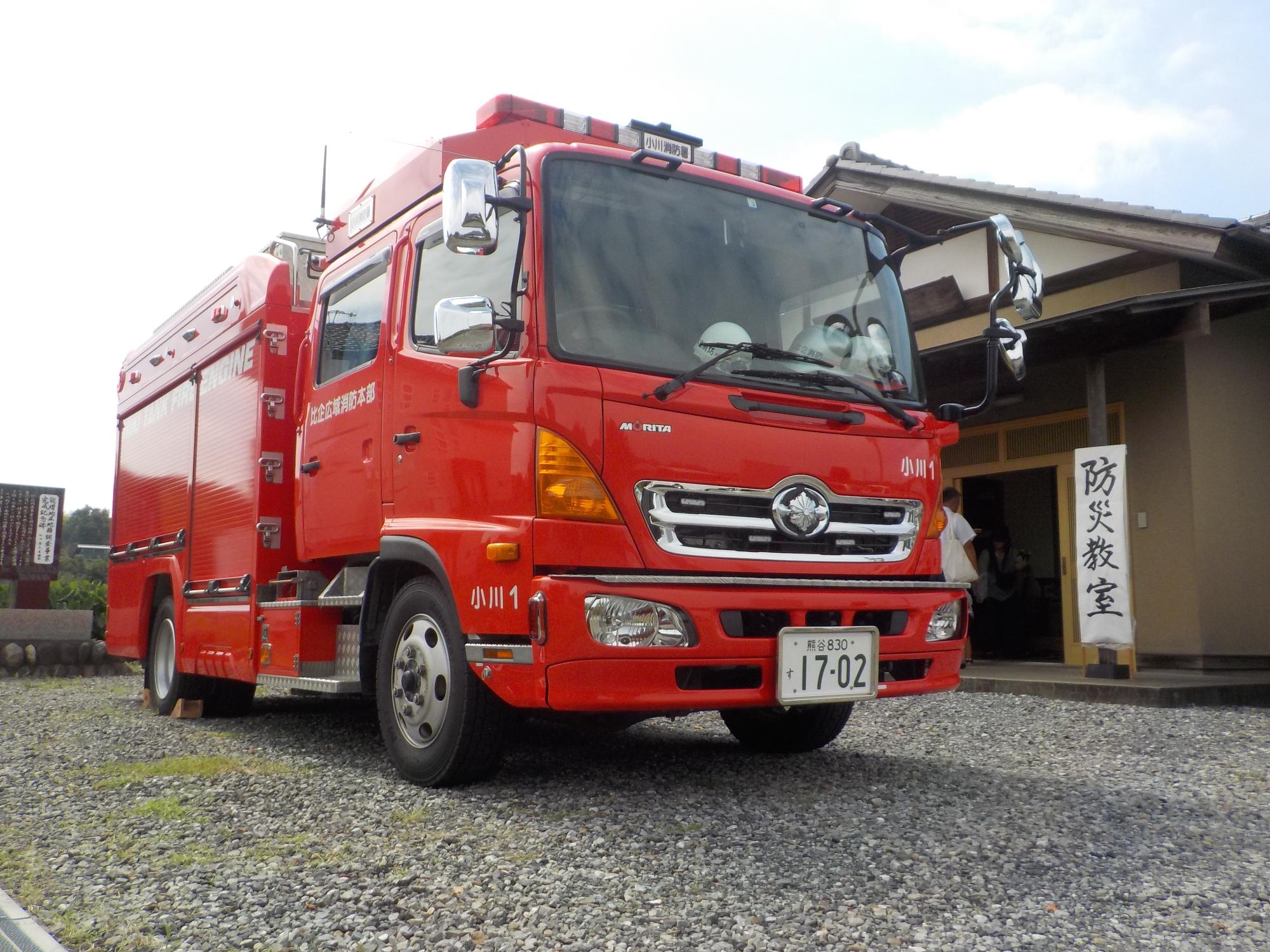 「防災教室」と書かれた看板が立て掛けられた能増公会所の前に停まっている綺麗に整備された消防車の写真