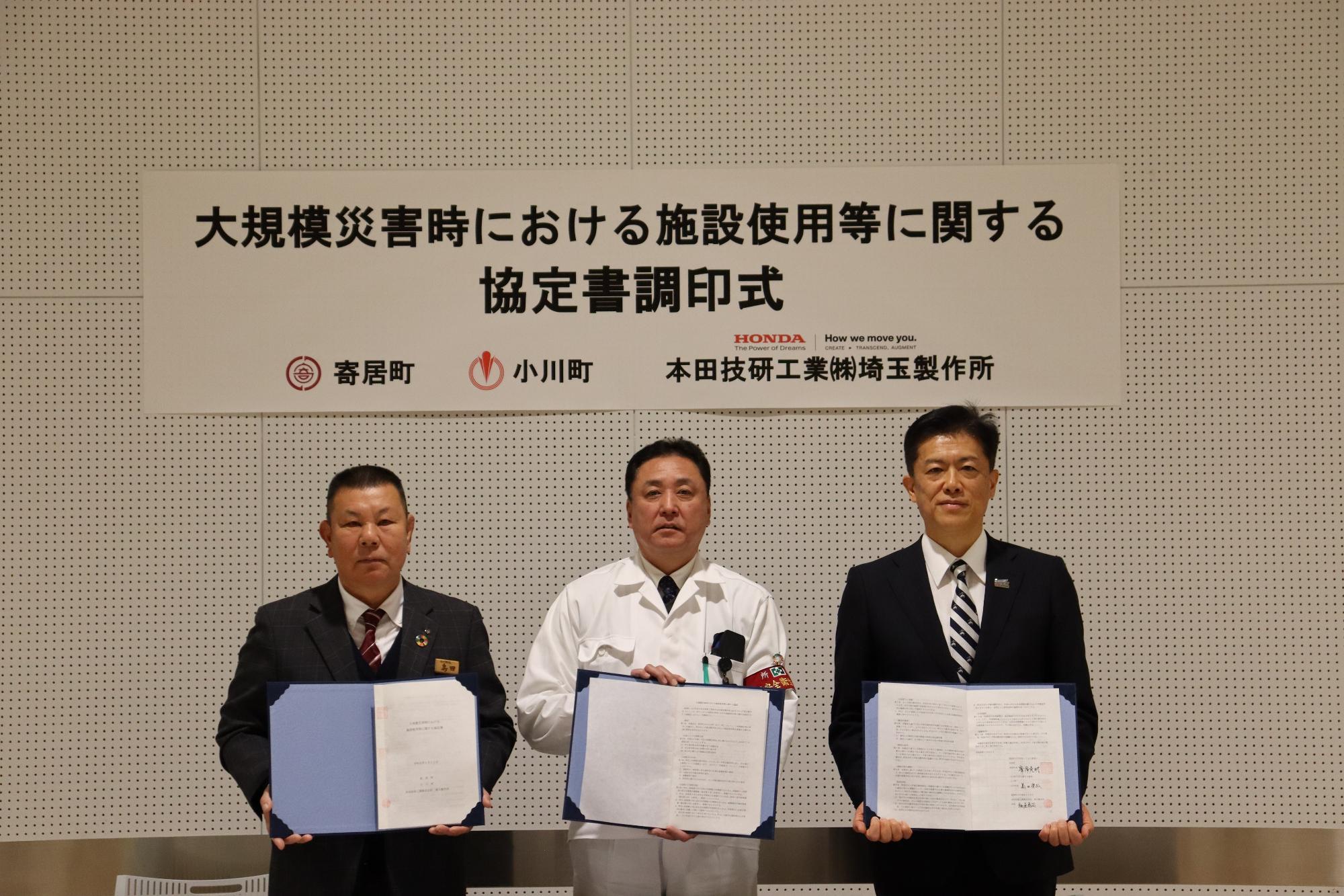 調印書を持った3名が記念撮影をしている写真