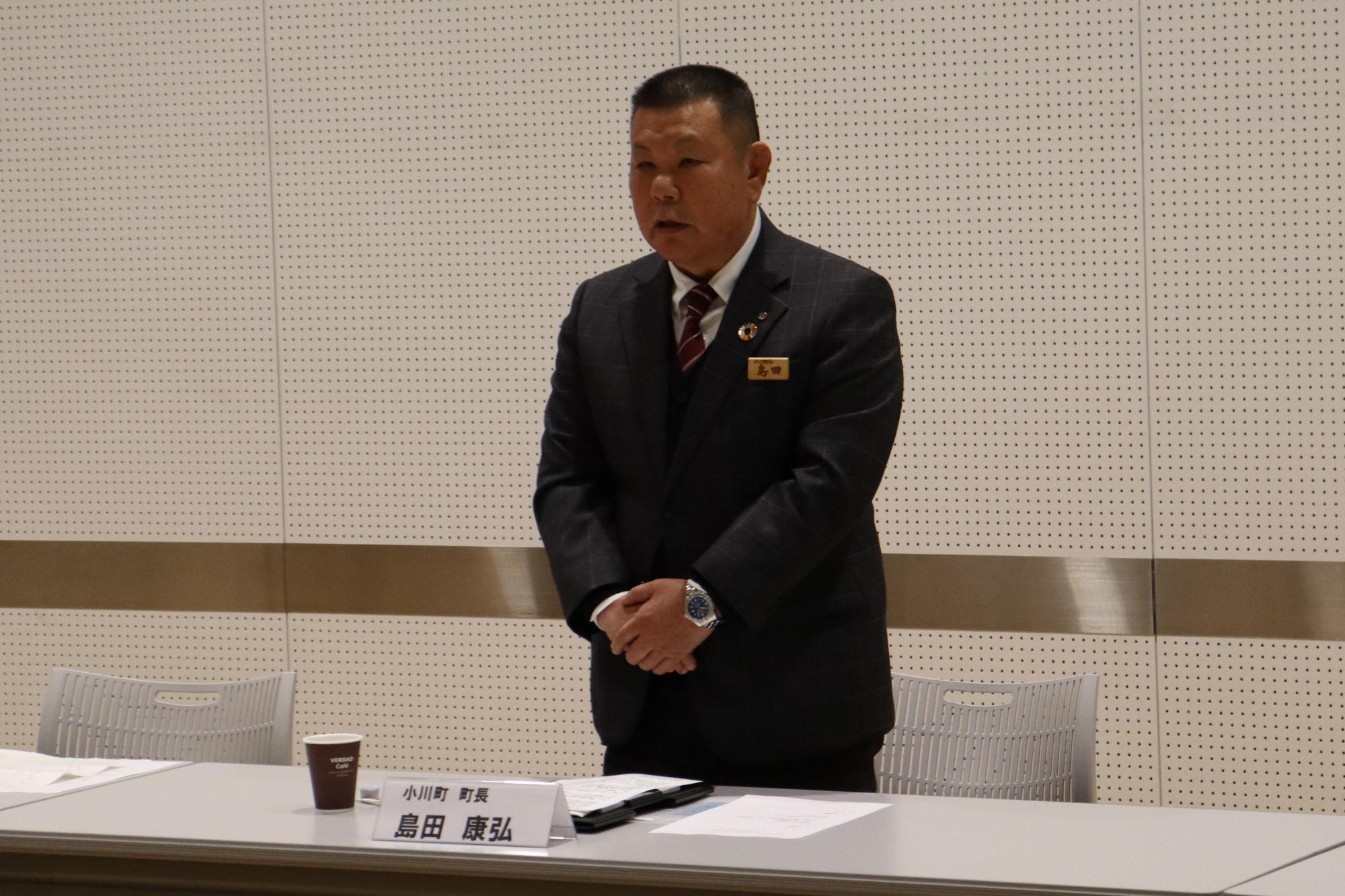 スーツ姿の島田町長が両手を前で重ね挨拶をしている写真