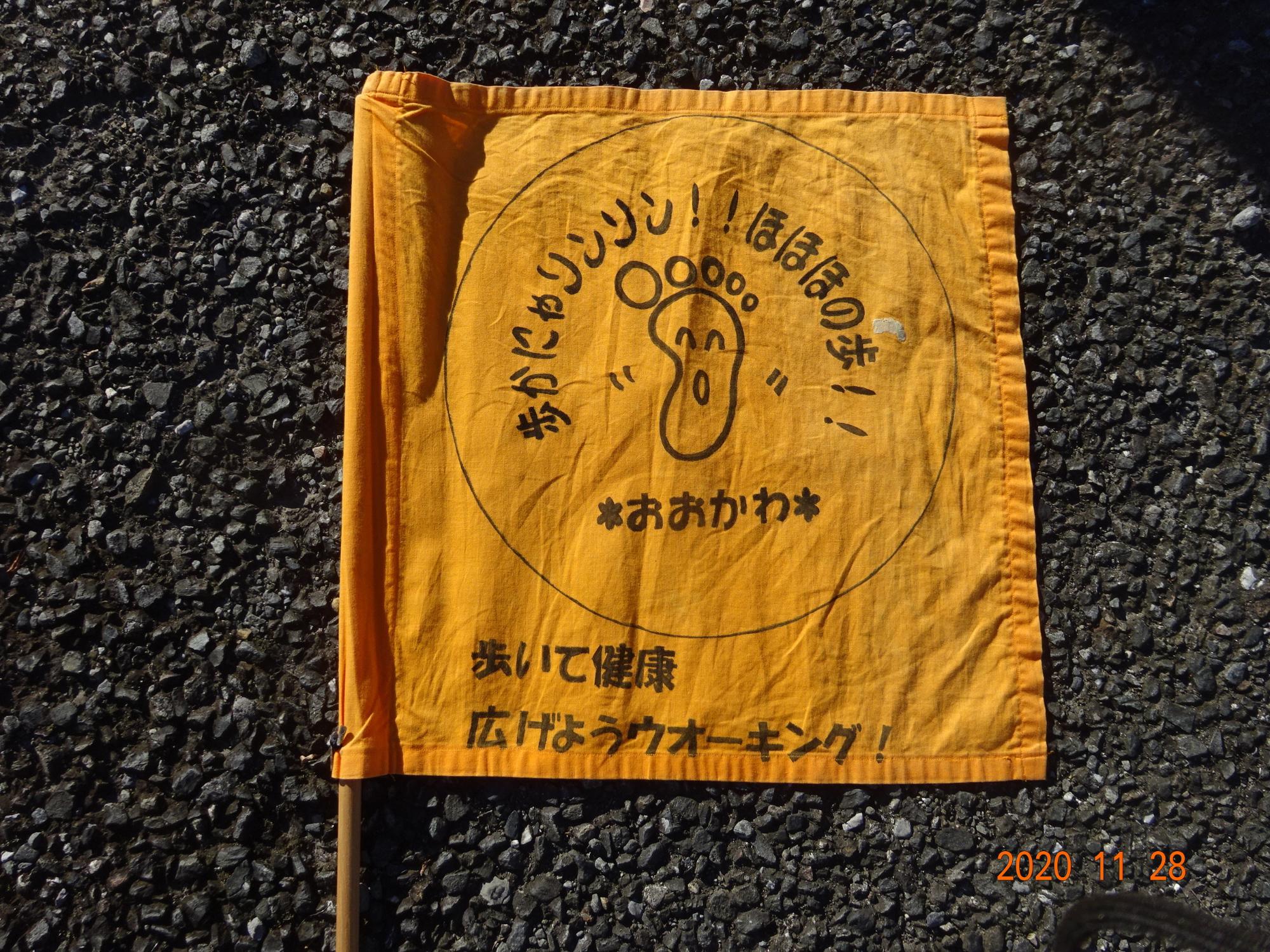 黄色地に足のマークとキャッチコピーが描かれた旗が路面に置かれた写真