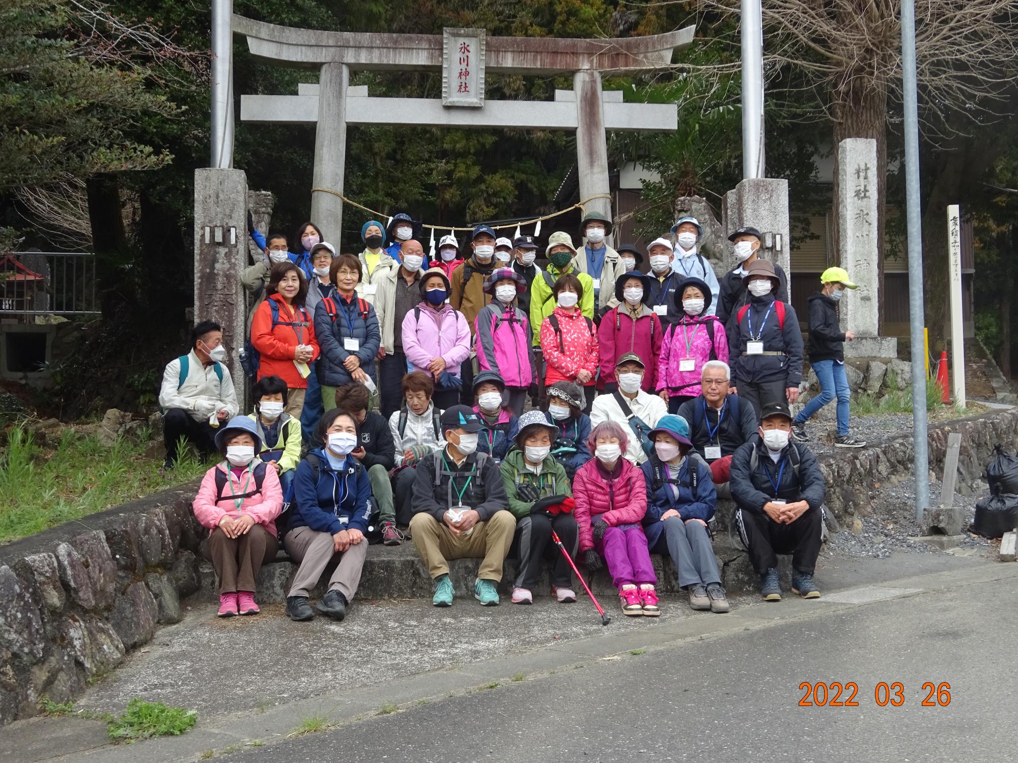 参加者たちが氷川神社の鳥居の前に並んでいる集合写真