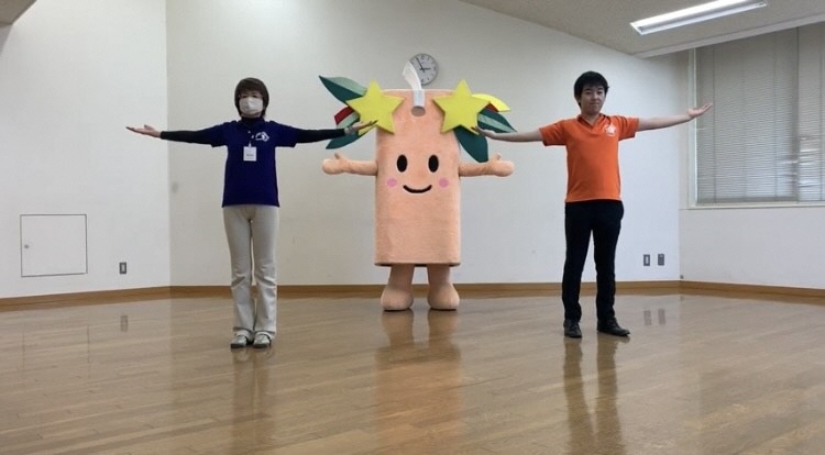 星夢（すたむ）ちゃんを中心に関係者2名が両脇に立ち、両手を肩の高さまで広げている写真（星夢（すたむ）ちゃんと踊ろう！ぴっかり千両体操（YouTube）のサイトへリンク