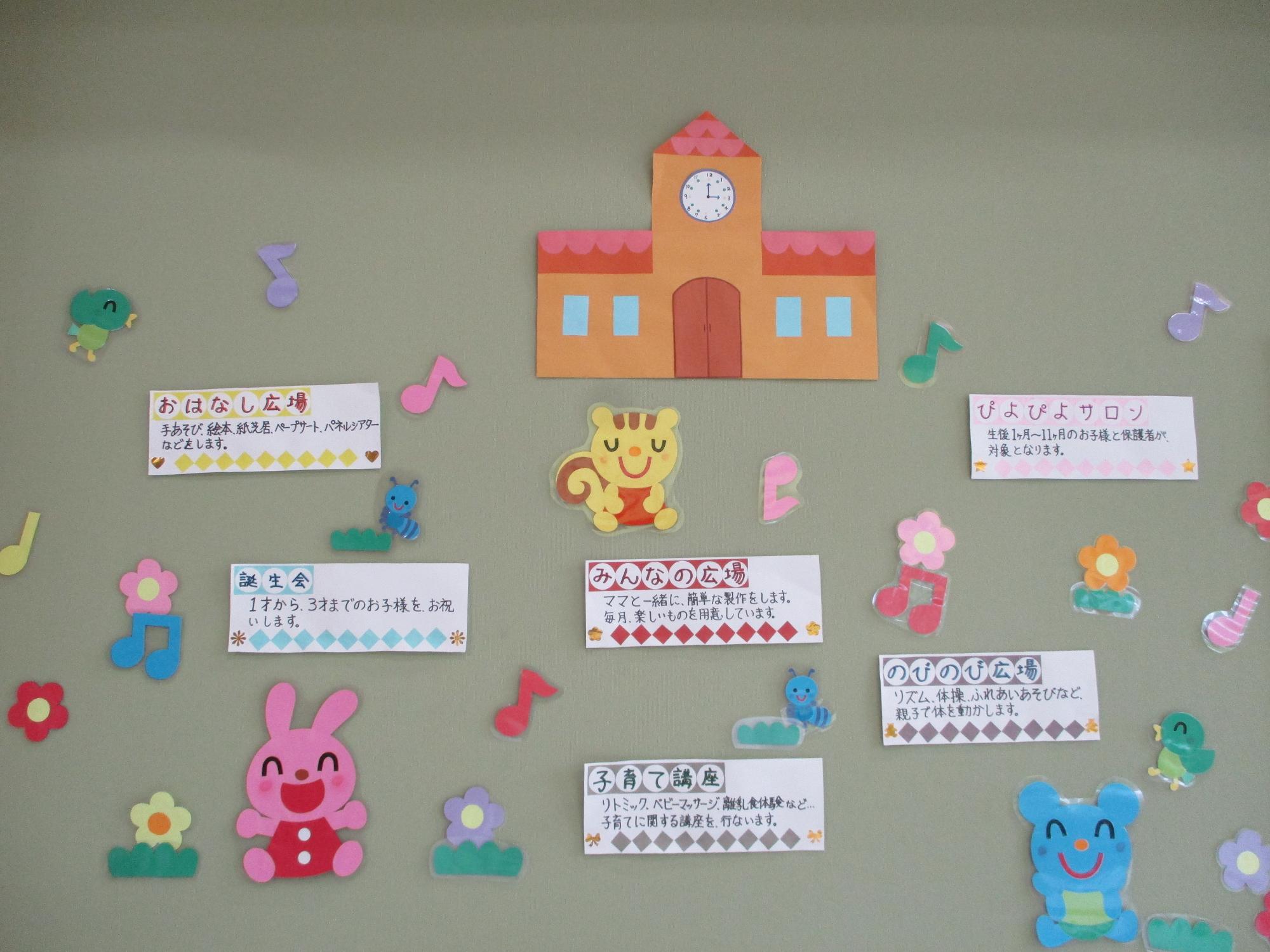 ホワイトボードに「家族であそぼう」と書かれた黄色の画用紙が一文字ずつ貼られ、「子育て支援センター」と書かれた黒色の画用紙で作られた機関車の荷台に「名前よび、手あそび、ふれあいあそび、できるかな？体操！」と手書きで書かれたピンク色の画用紙が貼られている写真